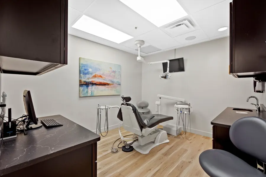 A treatment room at the Mt. Lebanon office, with the dental chair, a ceiling-mounted screen and a painting on the wall.